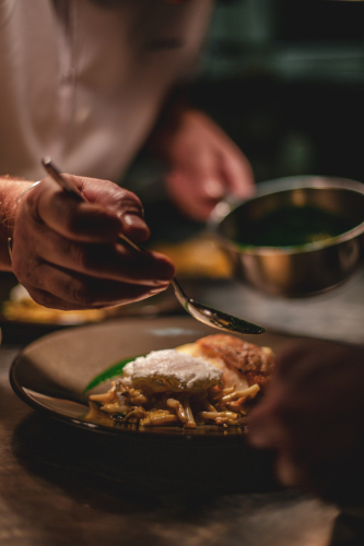 chef putting the final touches on a plate of poached eggs